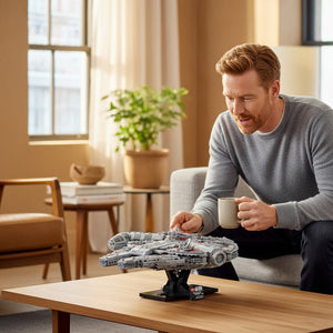 [lifestyle-person] A Brick Apart LEGO Star Wars Millennium Falcon model displayed on a stand while a man sits nearby holding a mug.