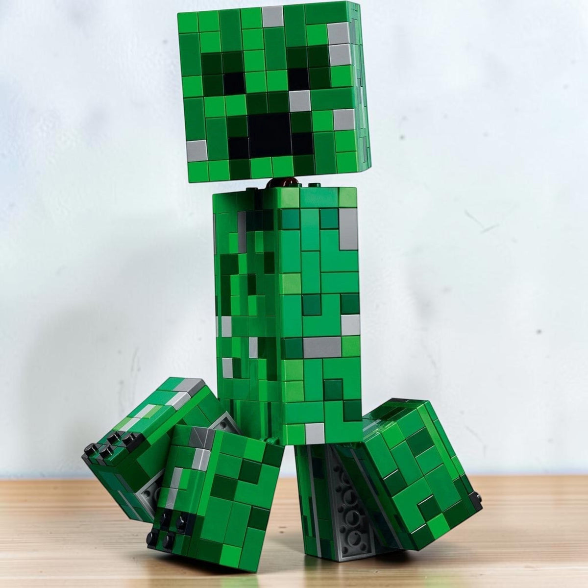 [lifestyle-shelf-built] A Brick Apart LEGO Minecraft The Creeper posable green action figure with movable legs and head on a white background.
