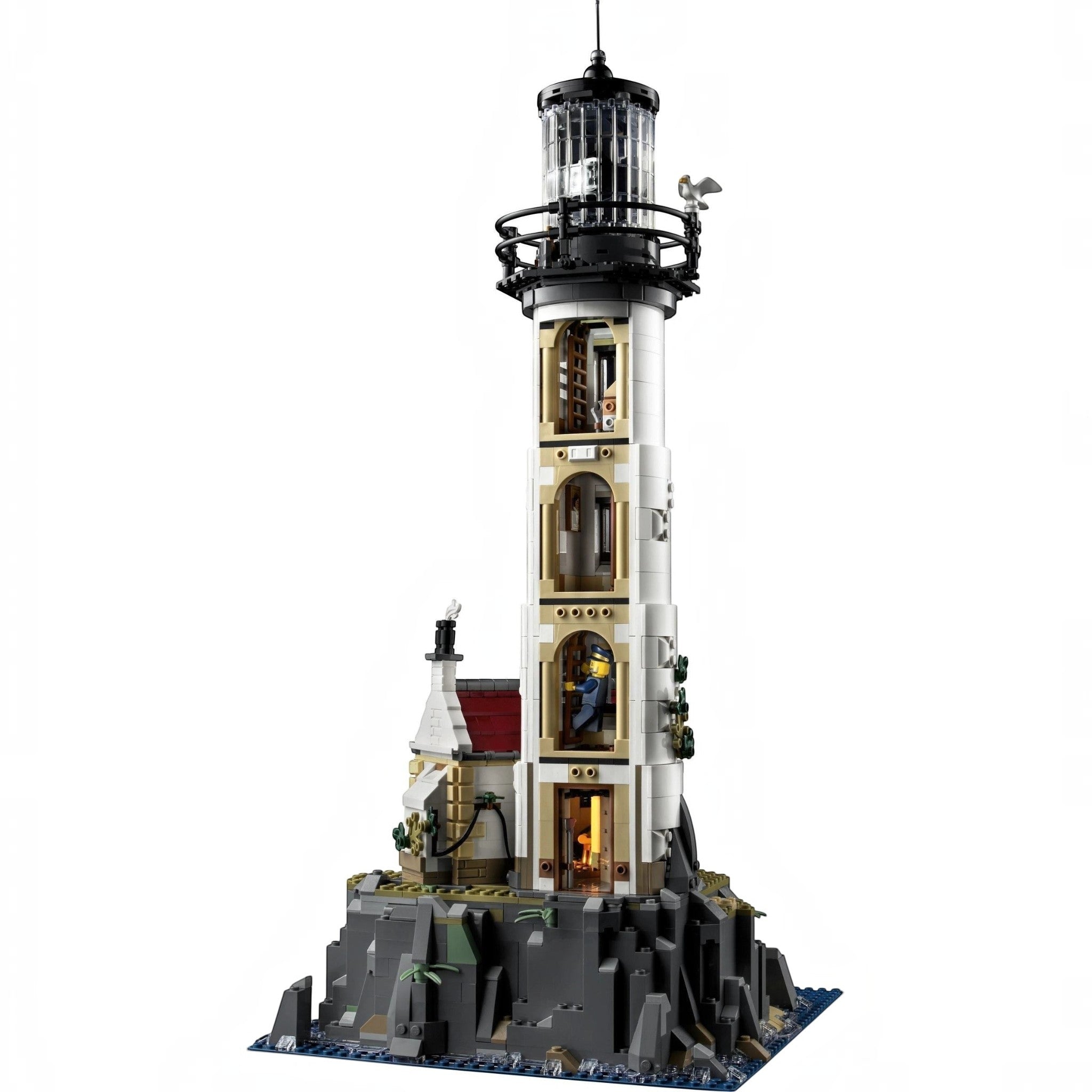 A Brick Apart LEGO Ideas Motorised Lighthouse set with rotating light, cottage, and rocky base on a white background.
