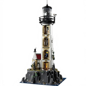 A Brick Apart LEGO Ideas Motorised Lighthouse set with rotating light, cottage, and rocky base on a white background.