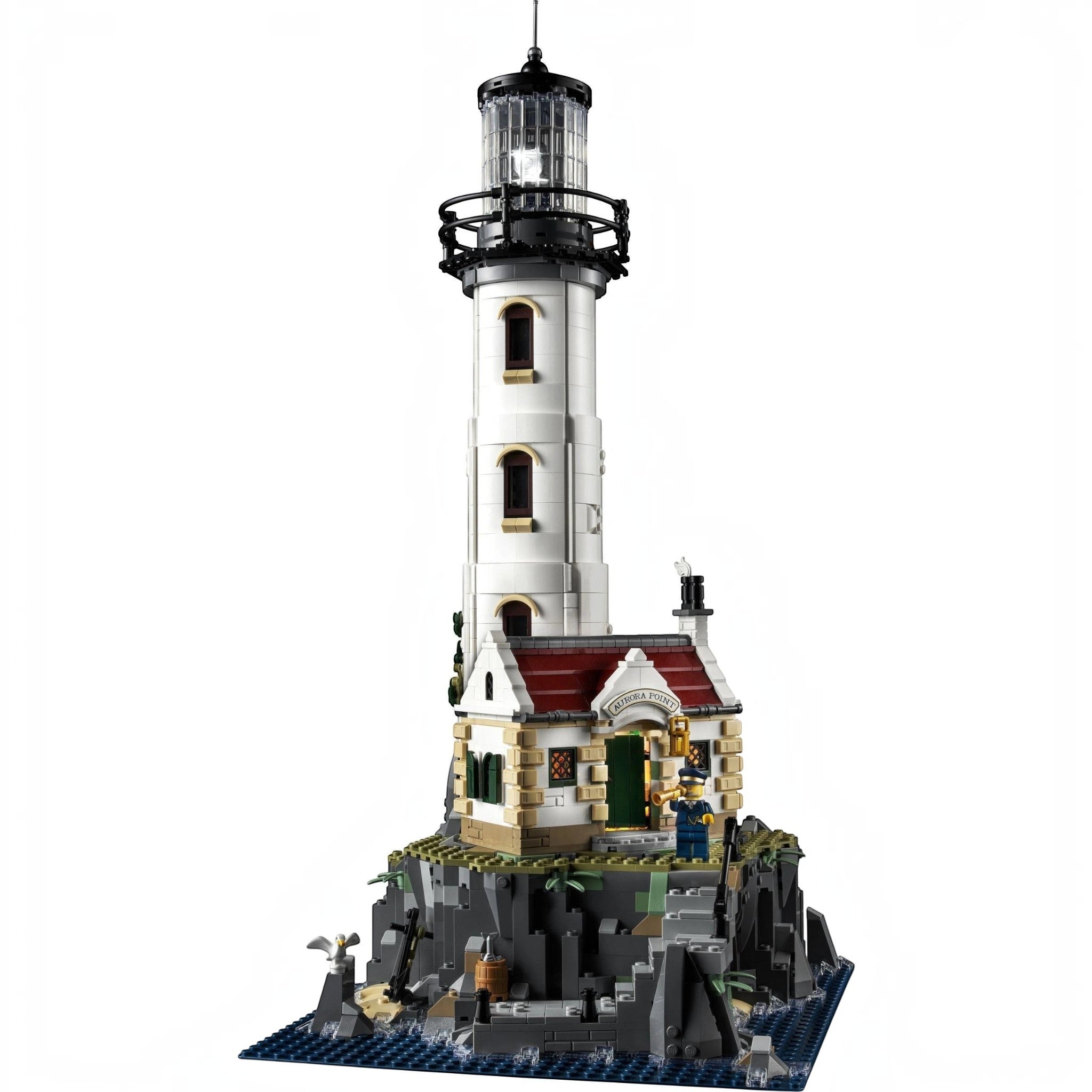 A Brick Apart LEGO Ideas Motorised Lighthouse set featuring a white tower, cottage, and rocky base with minifigures.