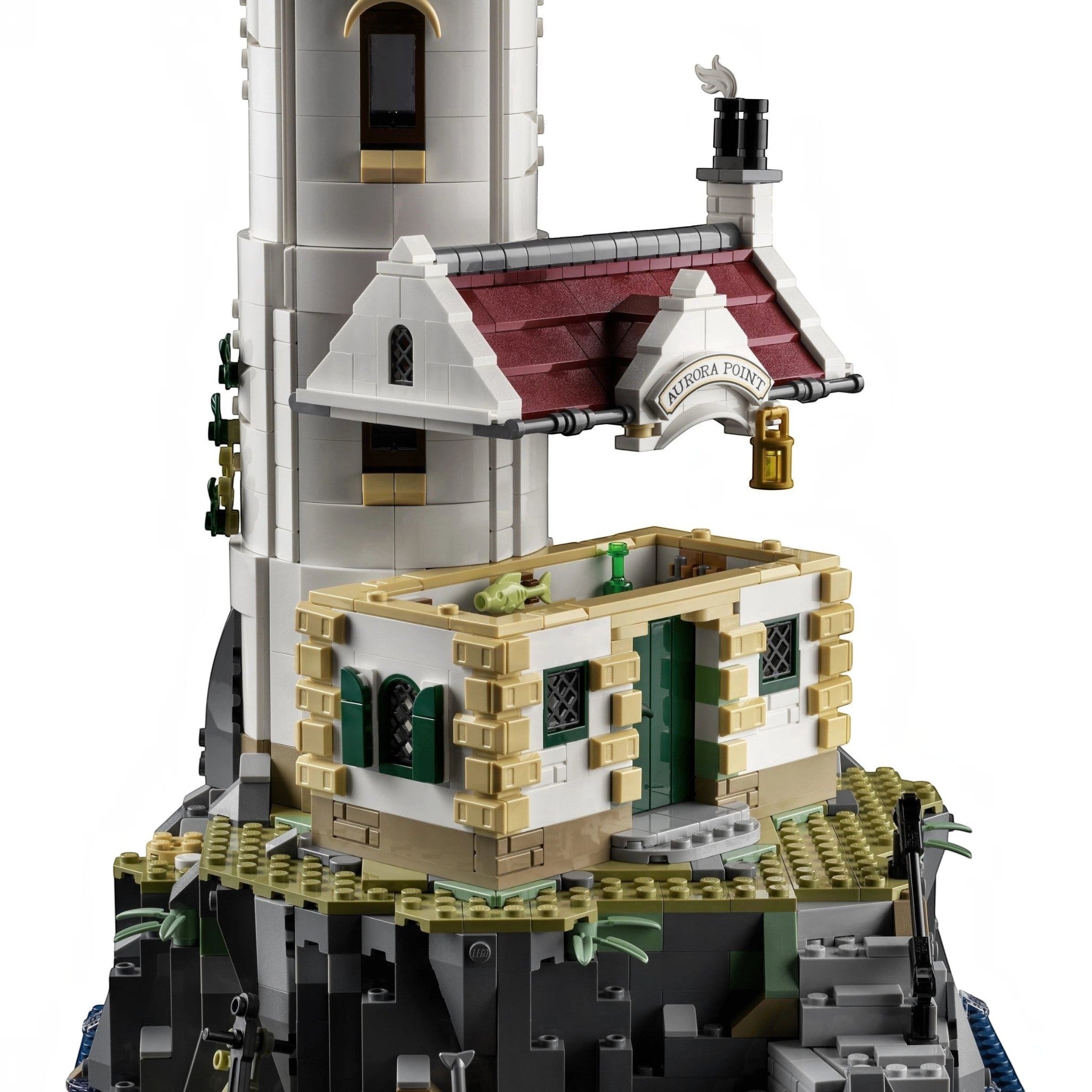 A Brick Apart LEGO Ideas Motorised Lighthouse set featuring a white tower, red-roofed cottage, and rocky base.