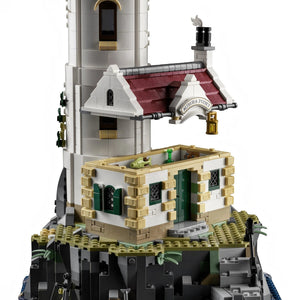 A Brick Apart LEGO Ideas Motorised Lighthouse set featuring a white tower, red-roofed cottage, and rocky base.