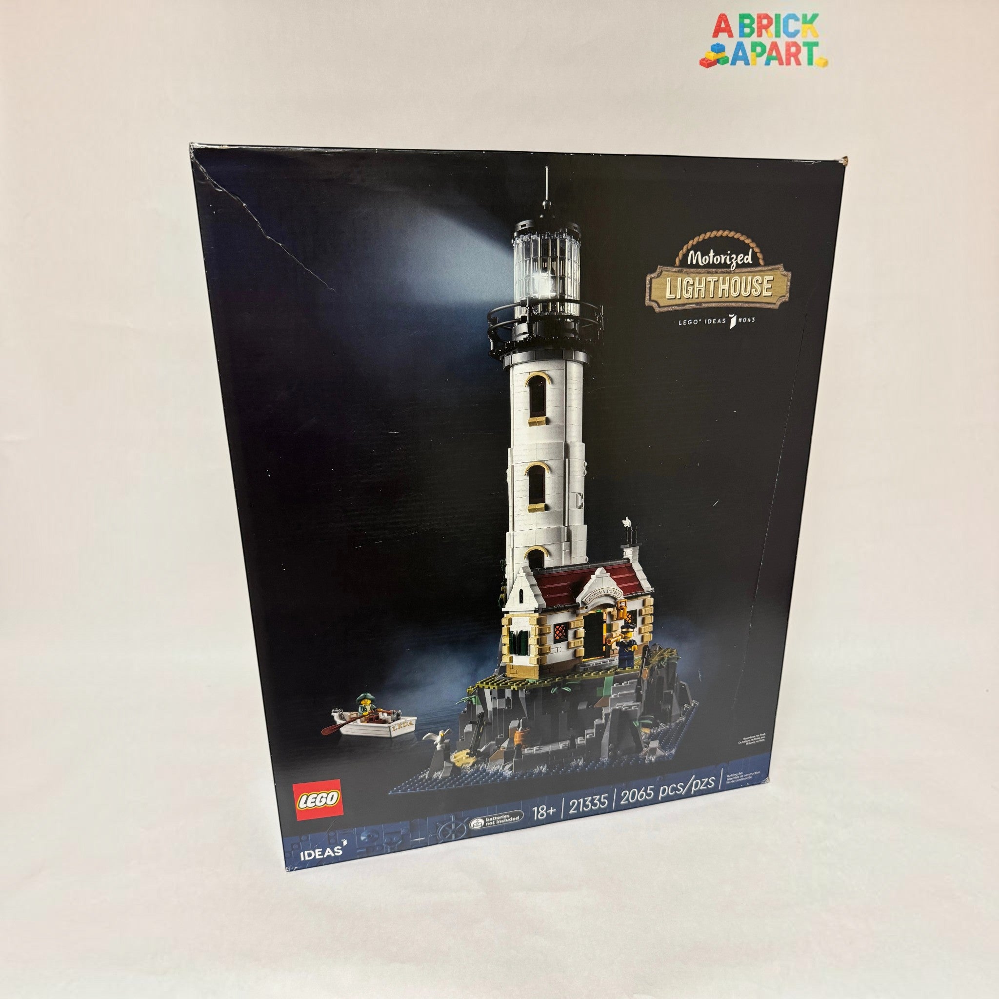 A Brick Apart LEGO Ideas Motorised Lighthouse set box showing the tall tower, cottage, and rowing boat on rocks.