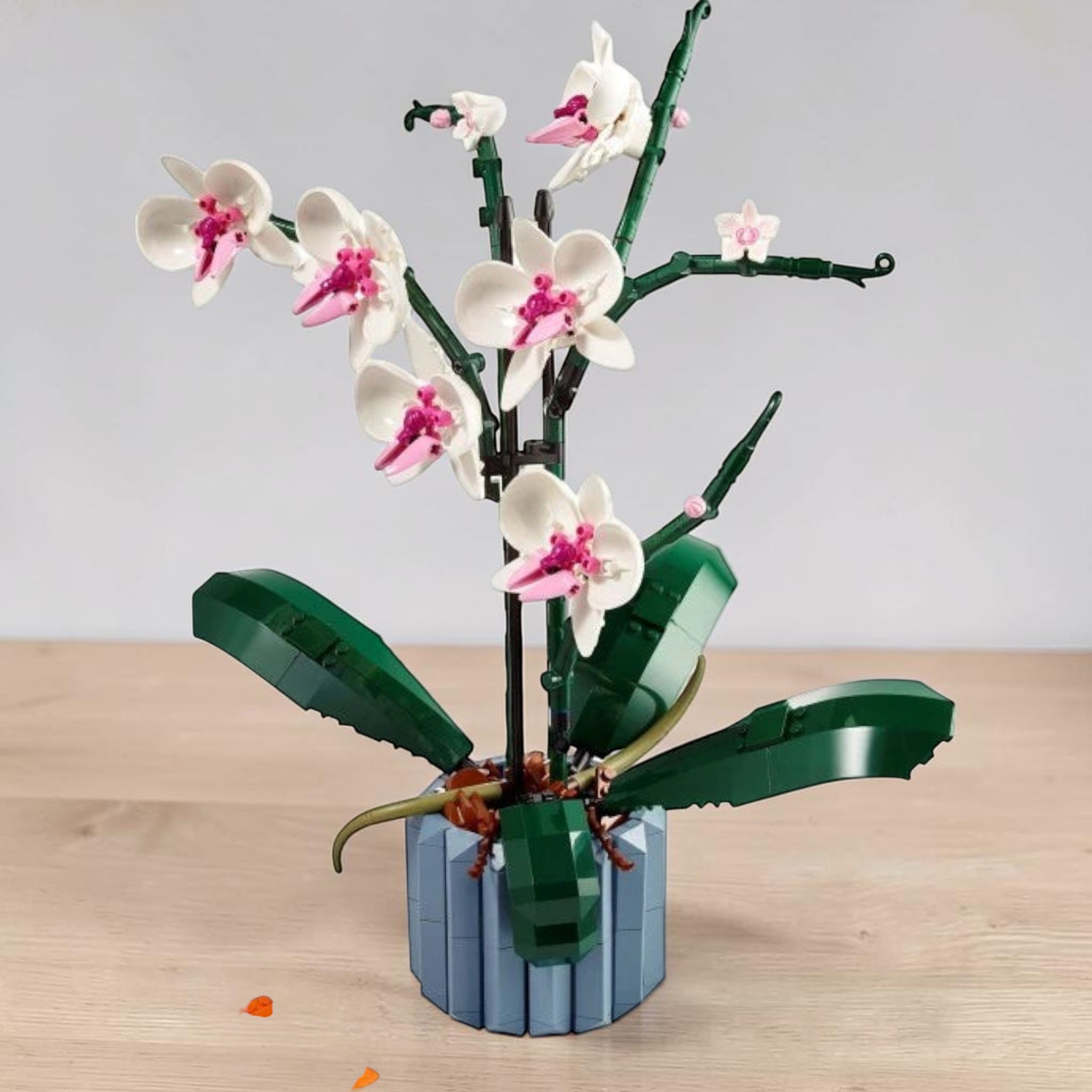 A Brick Apart LEGO Icons Orchid set featuring white and pink flowers in a blue fluted vase with green leaves.
