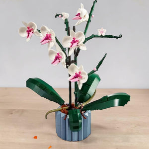 A Brick Apart LEGO Icons Orchid set featuring white and pink flowers in a blue fluted vase with green leaves.