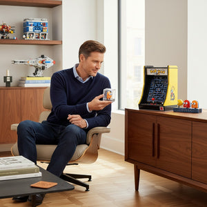 A Brick Apart LEGO Icons PAC-MAN Arcade set displayed on a wooden cabinet with a man holding a character figure.