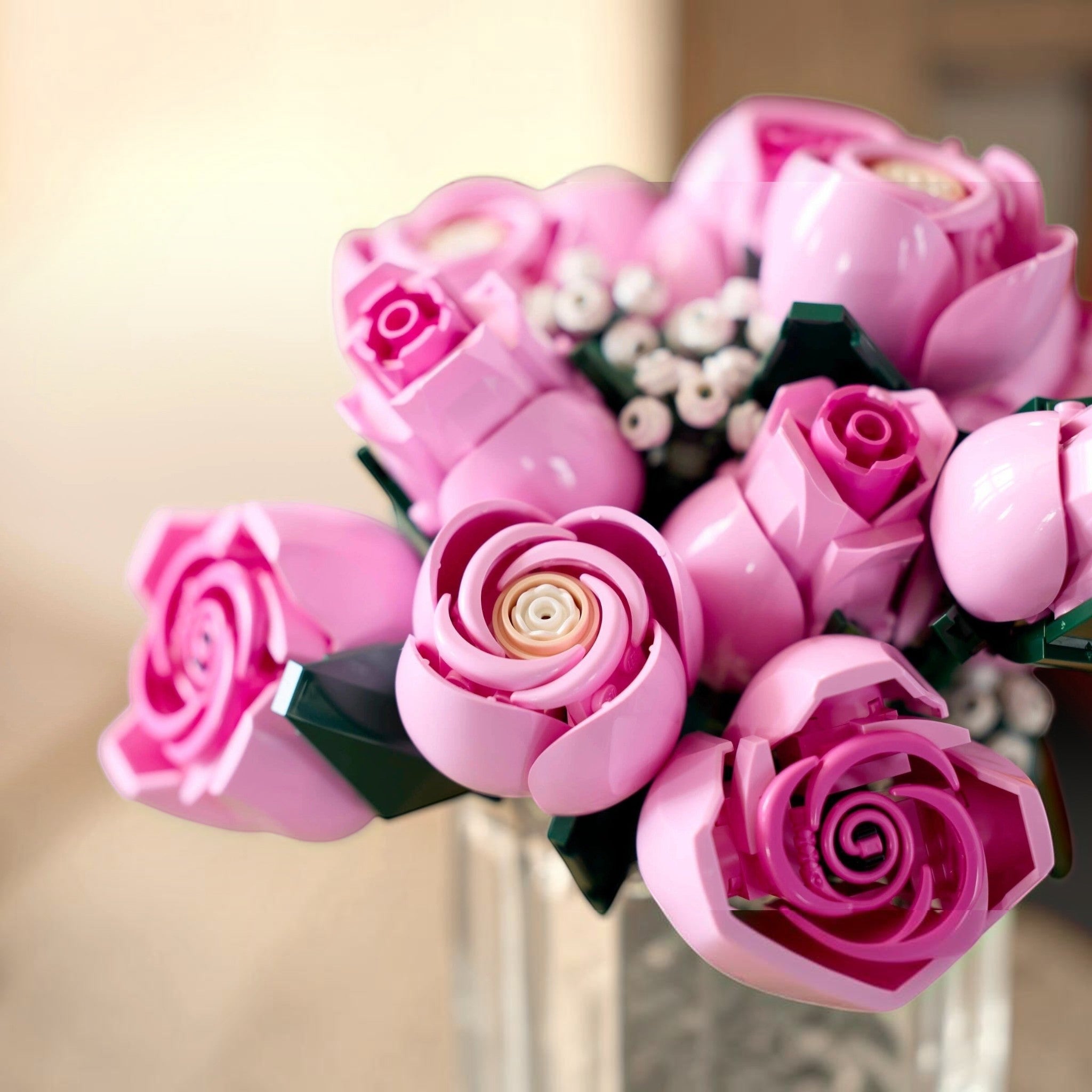A Brick Apart LEGO Botanicals bouquet featuring pink roses in various stages of bloom with white baby's-breath sprigs.