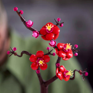A Brick Apart LEGO Icons Plum Blossom set featuring vibrant red and magenta flowers on a dark brown woody stem.