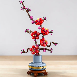 A Brick Apart LEGO Icons Plum Blossom set featuring red and magenta flowers on a woody stem in a pastel-blue pot.