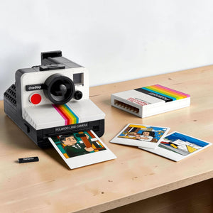 A Brick Apart LEGO Polaroid OneStep SX-70 camera model with a film pack and three illustrated photo prints.