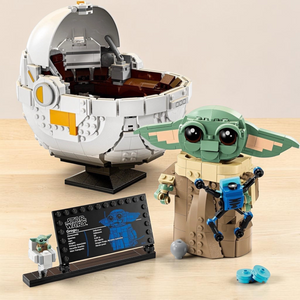 [lifestyle-shelf-built] A Brick Apart LEGO Star Wars Grogu buildable figure with hover pram, information plaque, and small accessories.