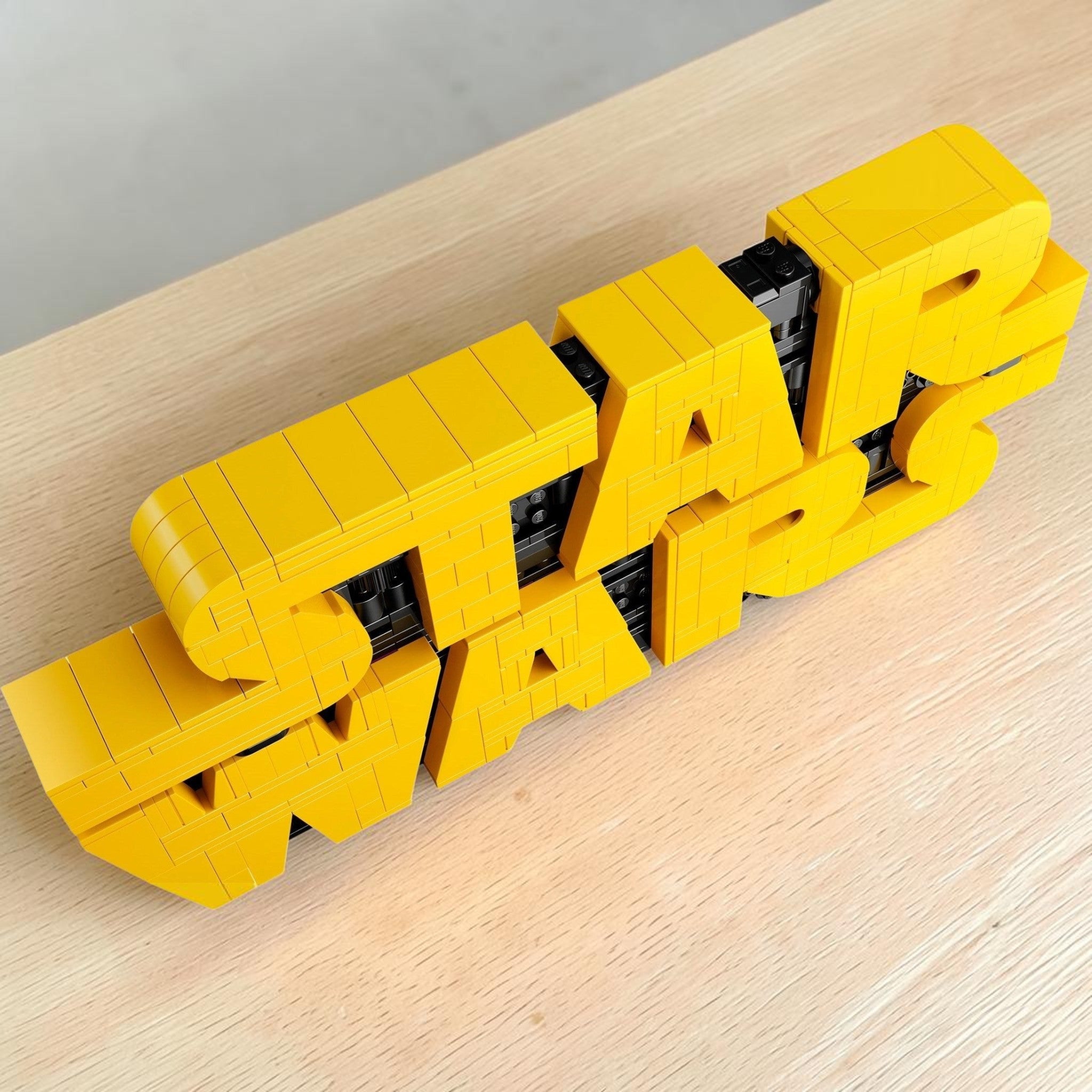A Brick Apart LEGO Star Wars logo 3D sign featuring yellow brick-built letters with black greebling details.