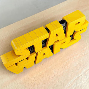 A Brick Apart LEGO Star Wars logo 3D sign featuring yellow brick-built letters with black greebling details.