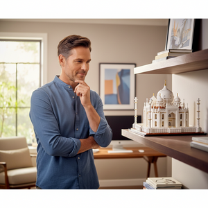 [lifestyle-person] A man admiring the A Brick Apart LEGO Architecture Taj Mahal model displayed on a wooden shelf in a home office.
