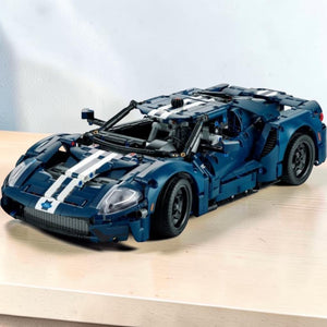 A Brick Apart LEGO Technic 2022 Ford GT model in dark blue with white racing stripes and intricate mechanical details.