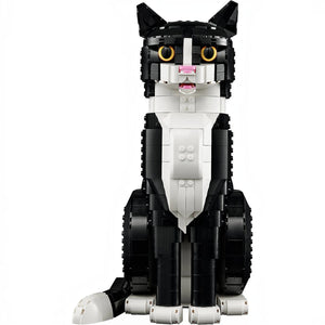 A Brick Apart LEGO Ideas Tuxedo Cat model with black and white bricks, yellow eyes, and an open mouth in a sitting pose.