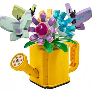 A Brick Apart LEGO Creator yellow watering can filled with colorful brick-built flowers and butterflies on sticks.
