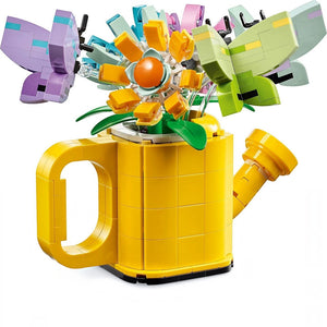 A Brick Apart LEGO Creator yellow watering can filled with colorful brick-built flowers and butterflies on sticks.