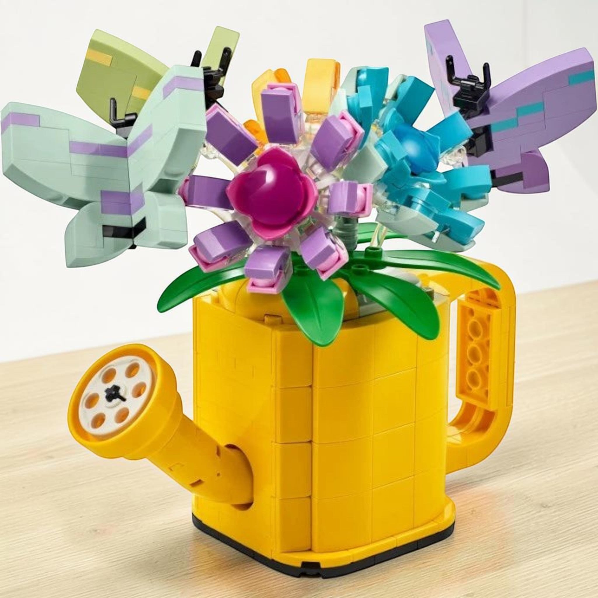 A Brick Apart LEGO Creator yellow watering can filled with colorful brick-built flowers and butterflies.