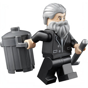 A Brick Apart LEGO Old Man Marley minifigure from the Home Alone set holding a grey trash can and a shovel.