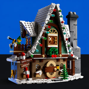 [built-blue-black] A detailed LEGO Christmas village house set built from multiple pieces, featuring a snowy roof, green walls, a chimney, decorative lights, a small tree, and a workshop sign, shown against a blue and black background.
