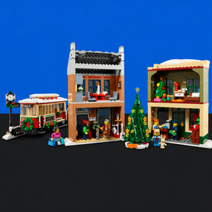 [built-blue-black] A LEGO holiday village set featuring a two-story brick building with a Christmas tree, a trolley, and two open-front shop buildings with minifigures, shown against a blue and black background.