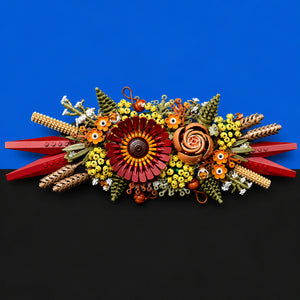 [built-blue-black] A colorful handmade floral arrangement made from pasta, green beans, rice, and small decorative elements, displayed against a split blue and black background.