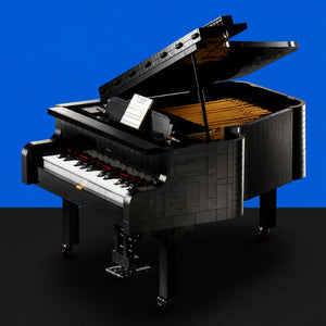 [built-blue-black] A LEGO-style grand piano built from black and gray bricks, with white and black keys, an open lid, and a yellow interior, photographed against a blue background with a black floor.
