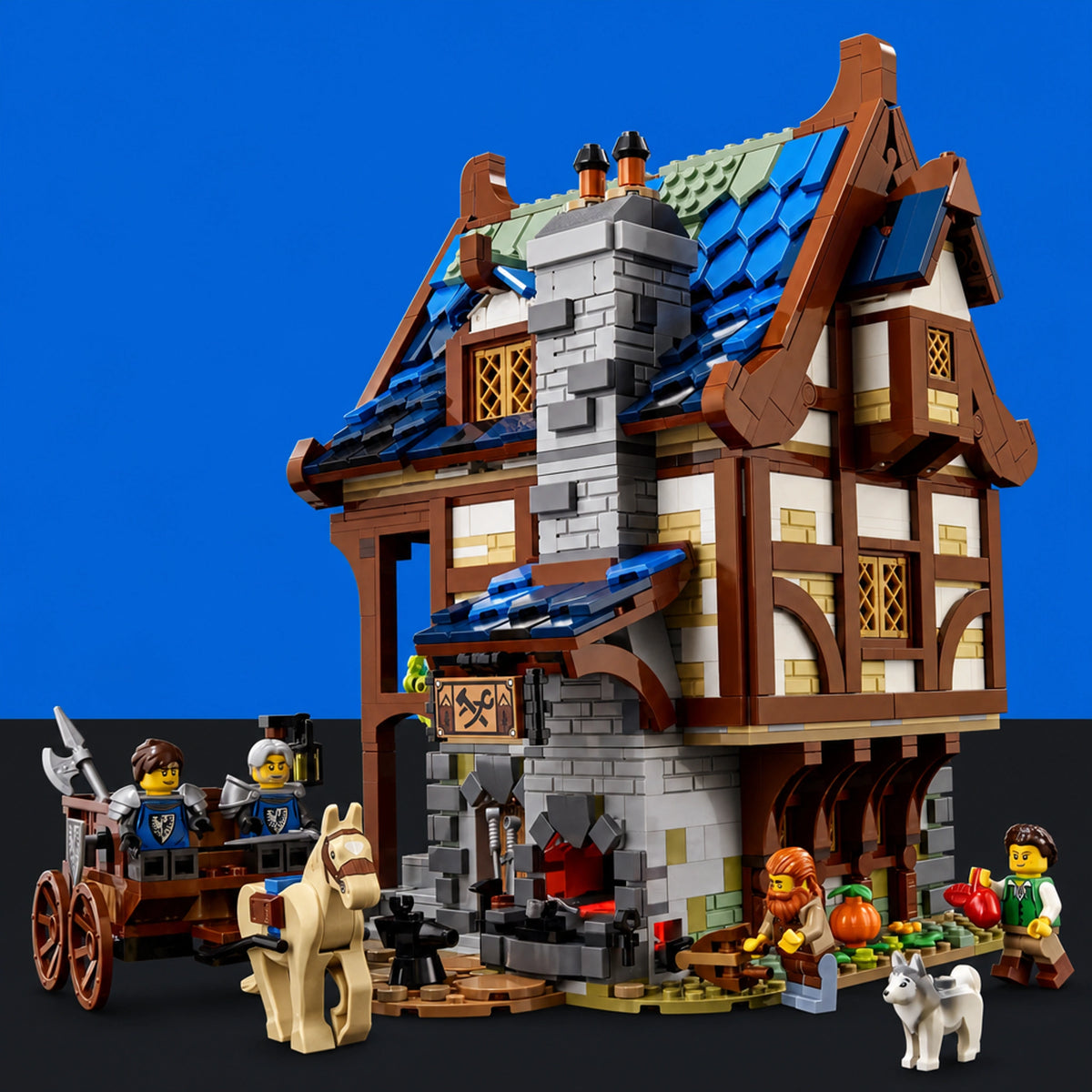 [built-blue-black] A detailed LEGO medieval-style building set with a two-story stone and timber house, blue roof tiles, a fireplace, a cart with minifigures, a horse, and small accessory figures, photographed against a blue and black background.