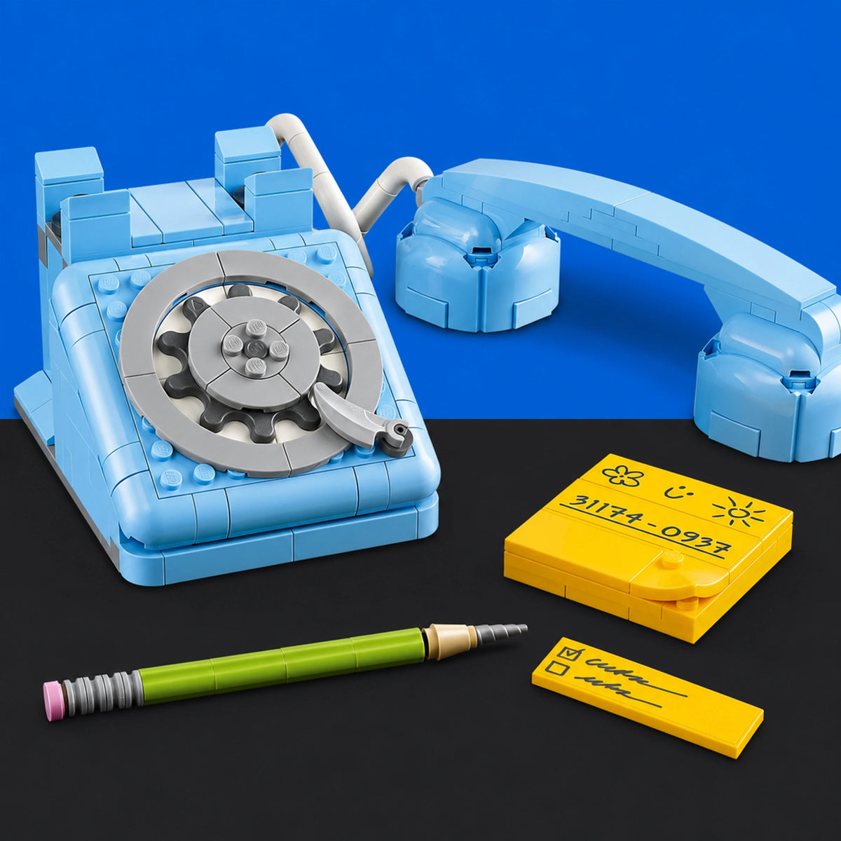 [built-blue-black] A light blue toy rotary telephone set with a matching handpiece, shown alongside a green pencil and two yellow notepad-like pieces on a split black and blue background.