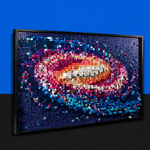 [built-blue-black] A framed wall art piece made of many colorful 3D letters and numbers, forming a galaxy or nebula design, shown against a blue and black background.
