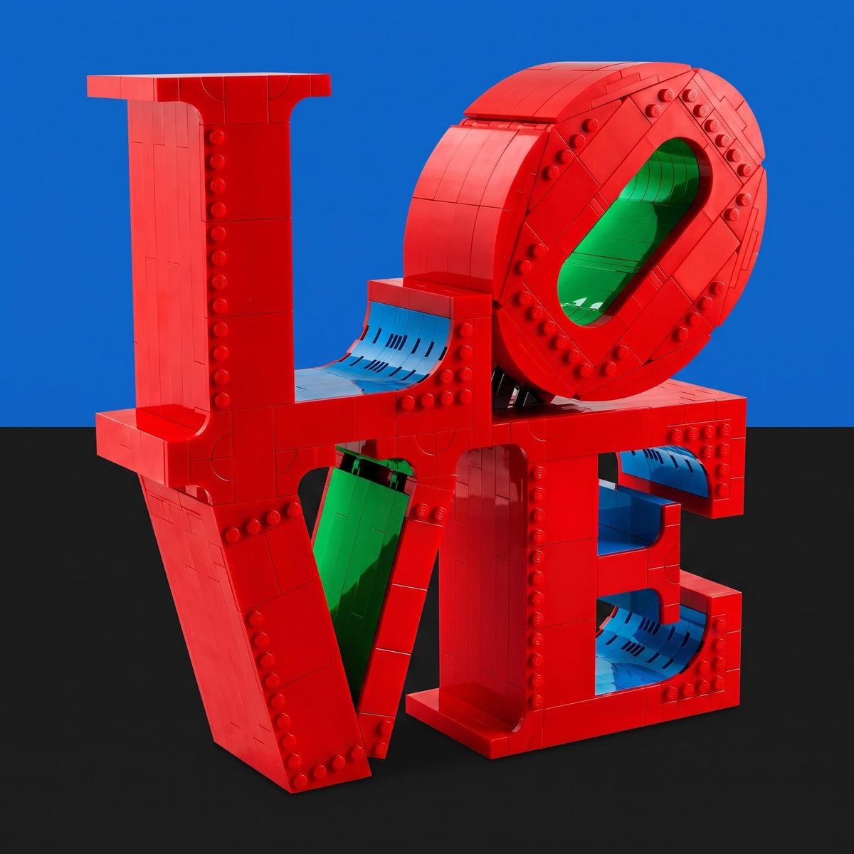 [built-blue-black] A red LEGO-style sculpture spelling LOVE, with each letter featuring rivet details and colorful translucent inner panels in blue and green, set against a split blue and black background.