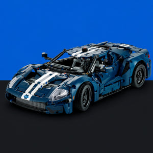 [built-blue-black] A blue and white building-block toy sports car, resembling a Ford GT, displayed on a black surface against a solid blue background.