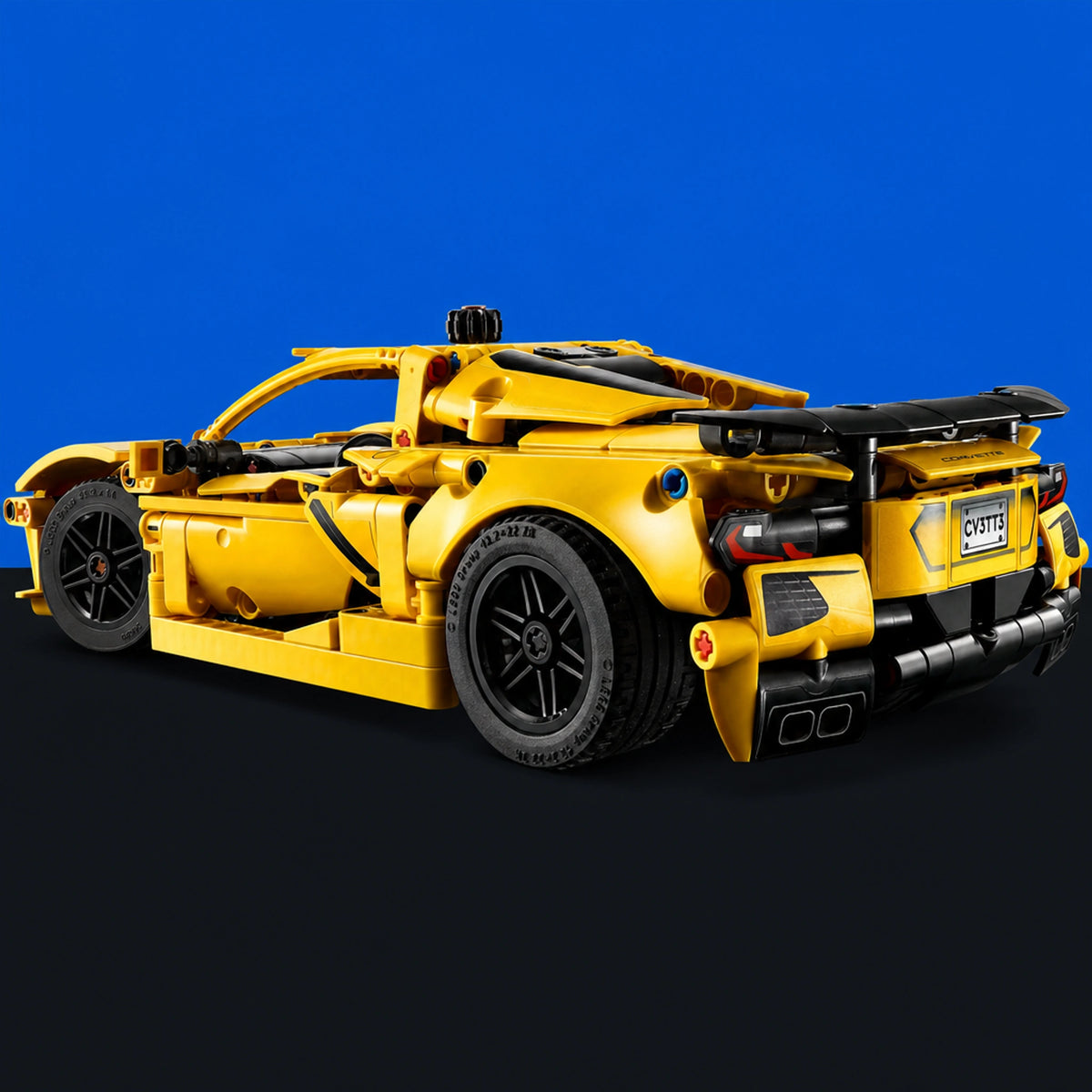 [built-blue-black] A yellow and black LEGO Technic Hypercar Siorra model, shown from a rear three-quarter angle against a solid blue background fading to black at the bottom.
